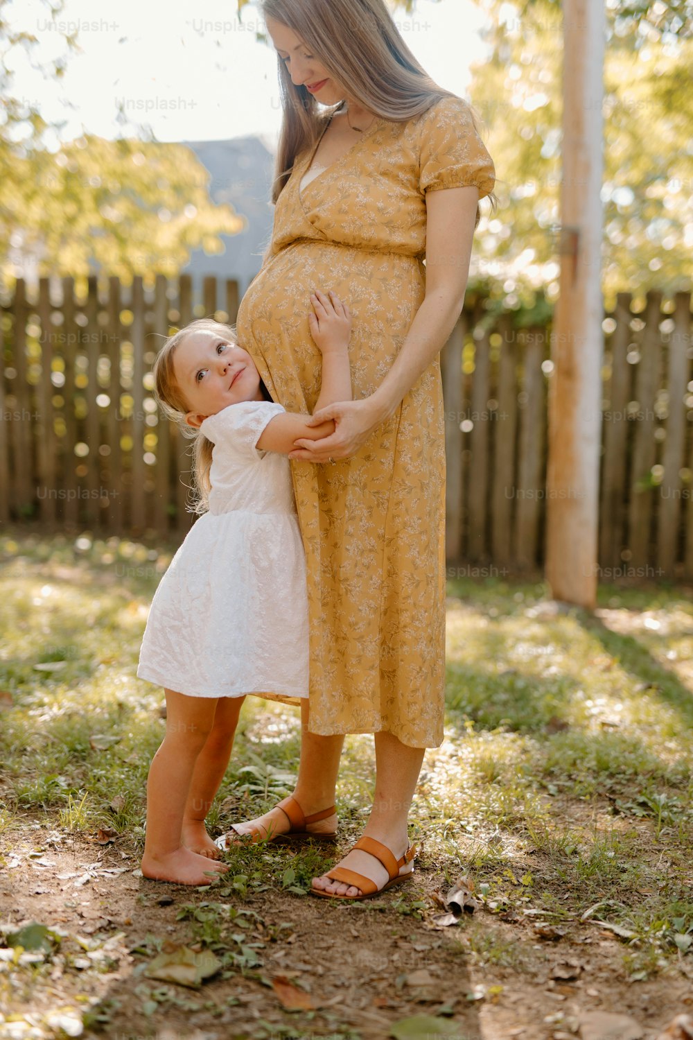 Una mujer embarazada sosteniendo a una niña en sus brazos