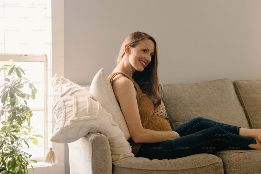 uma mulher sentada em um sofá sorrindo para a câmera