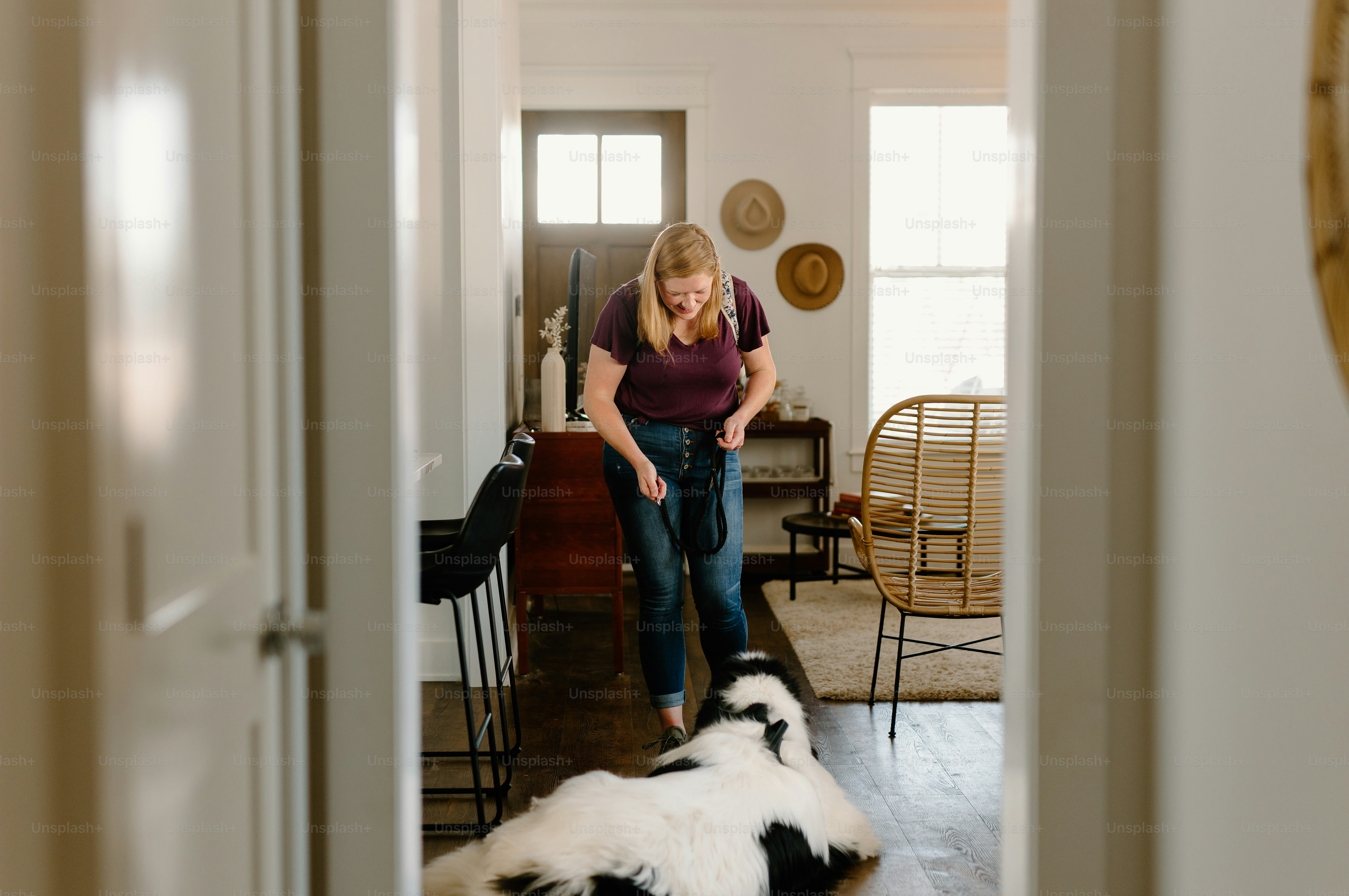 a woman standing in a living room next to a black and white dog