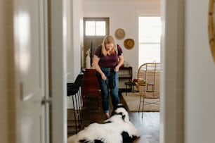 a woman standing in a living room next to a black and white dog