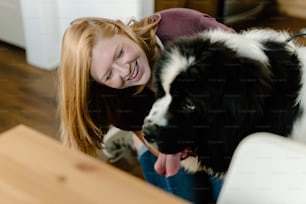 a woman sitting next to a black and white dog