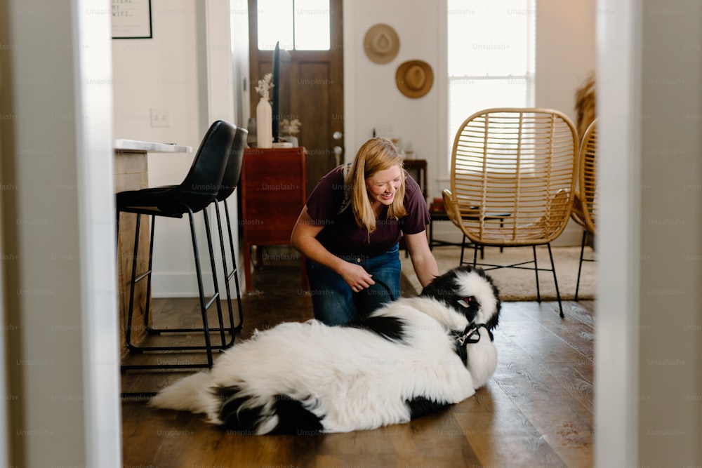 a woman kneeling down next to two black and white dogs