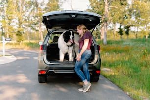 a woman sitting in the back of a van with a dog