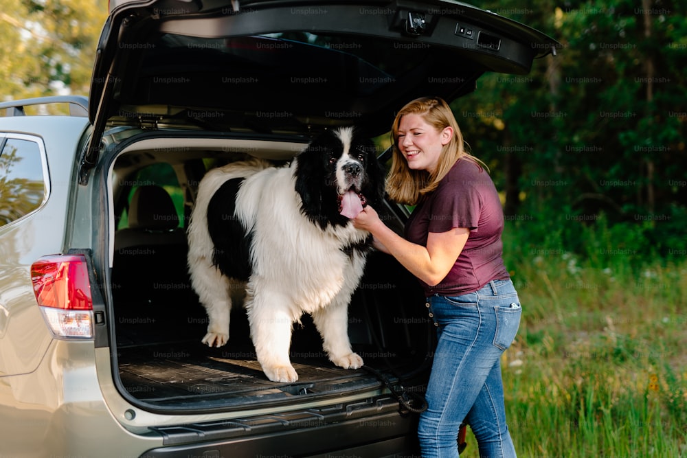 a woman standing next to a dog in the back of a van