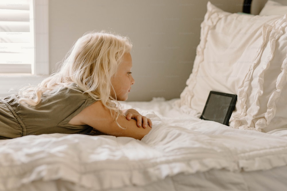 a woman laying on top of a bed next to pillows