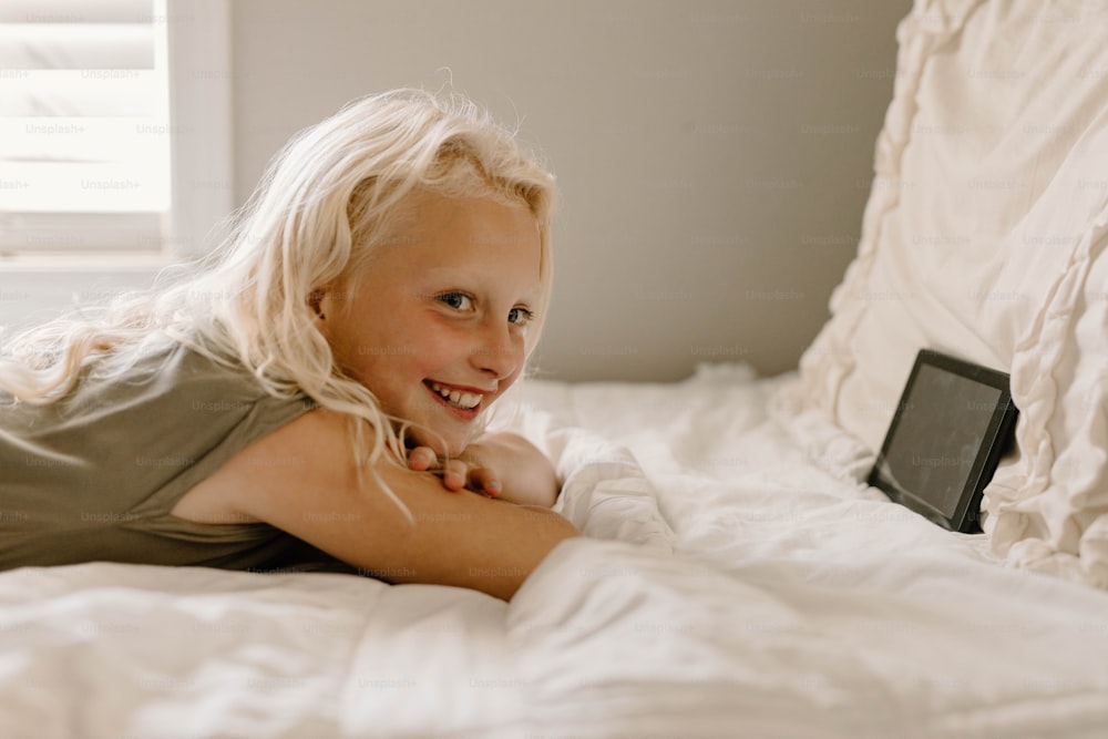 Una niña acostada en una cama con sábanas blancas