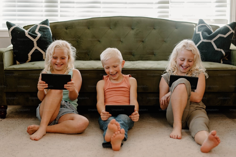 three children sitting on the floor with their ipads
