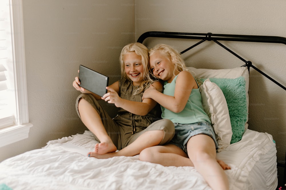 a couple of girls sitting on top of a bed