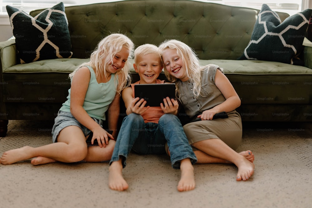 three girls sitting on the floor looking at a tablet