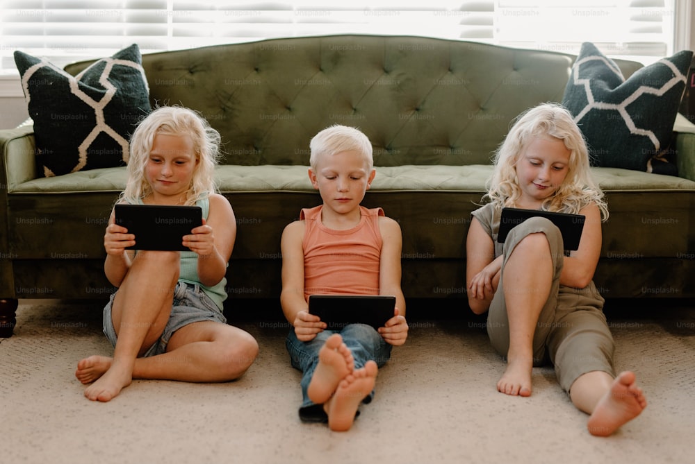 세 명의 어린 소녀가 아이패드를 들고 바닥에 앉아 있다