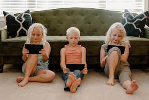 Trois petites filles assises par terre avec leurs iPads