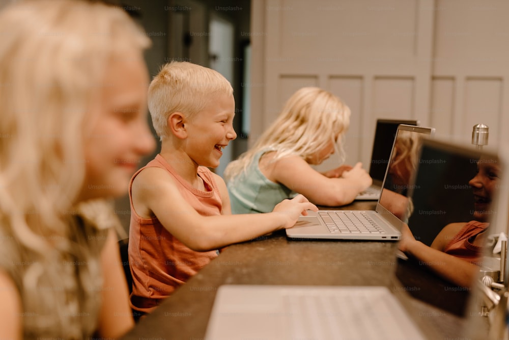 a group of children sitting at a table with a laptop