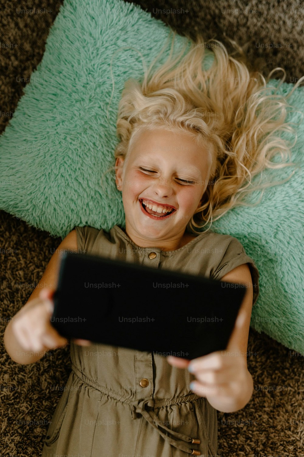 a little girl laying on the floor with a tablet