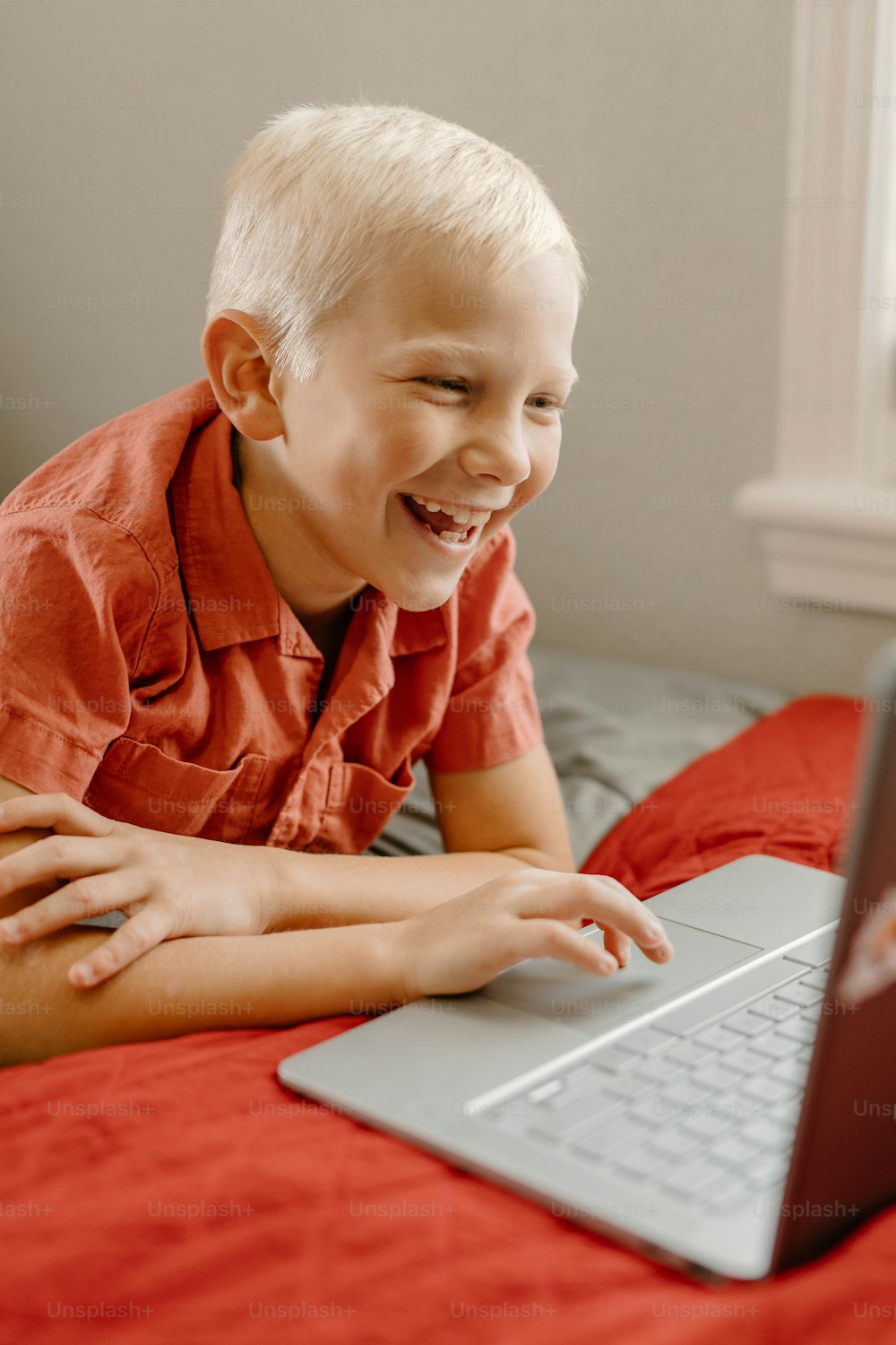 a young boy smiles as he looks at a laptop