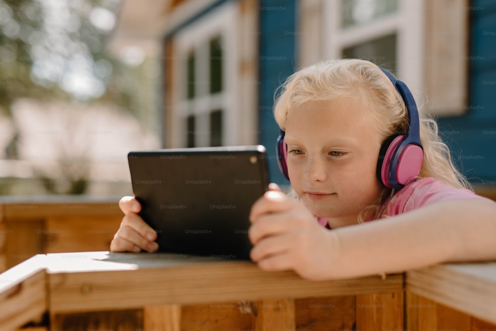 a little girl wearing headphones looking at a tablet