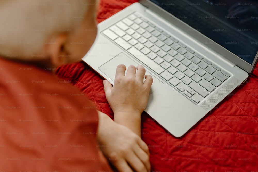 침대에서 노트북 컴퓨터를 사용하는 어린 ��소년
