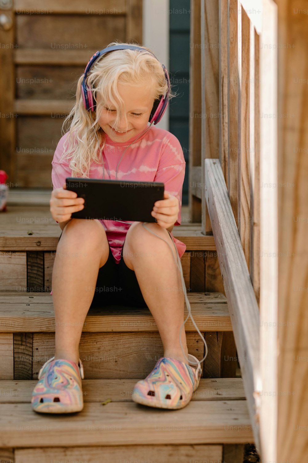 a little girl sitting on the steps with a tablet