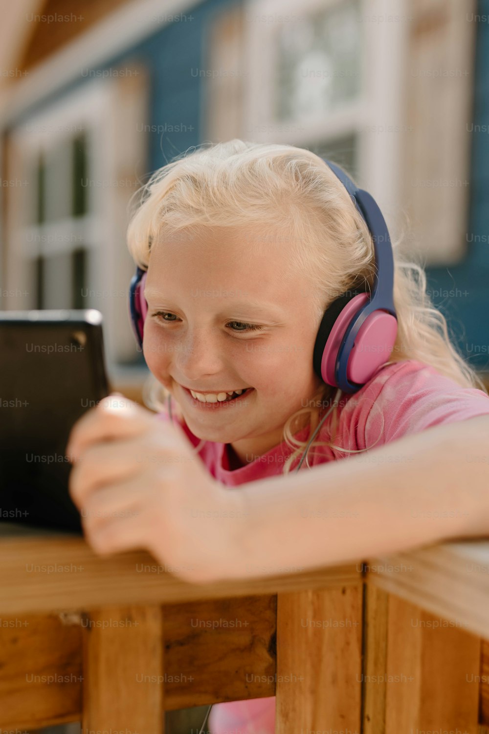 a little girl wearing headphones and looking at a tablet