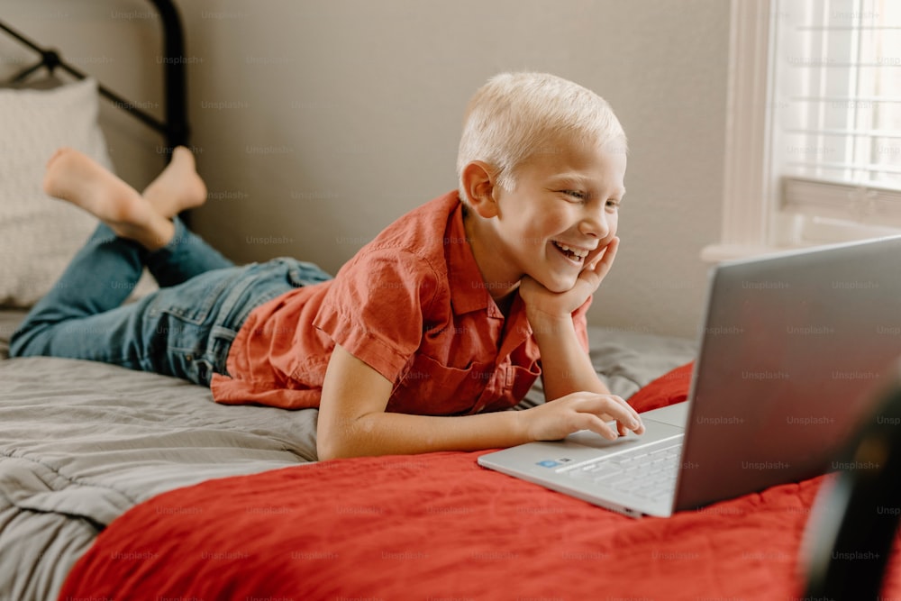 a young boy laying on a bed with a laptop