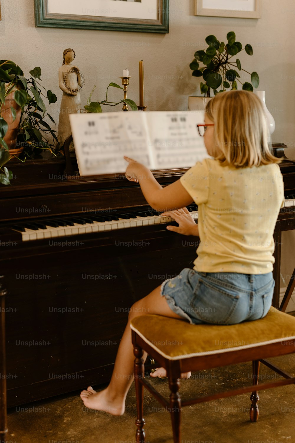 a little girl sitting on a chair playing a piano
