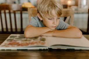 Ein kleiner Junge, der an einem Tisch sitzt und ein Buch liest