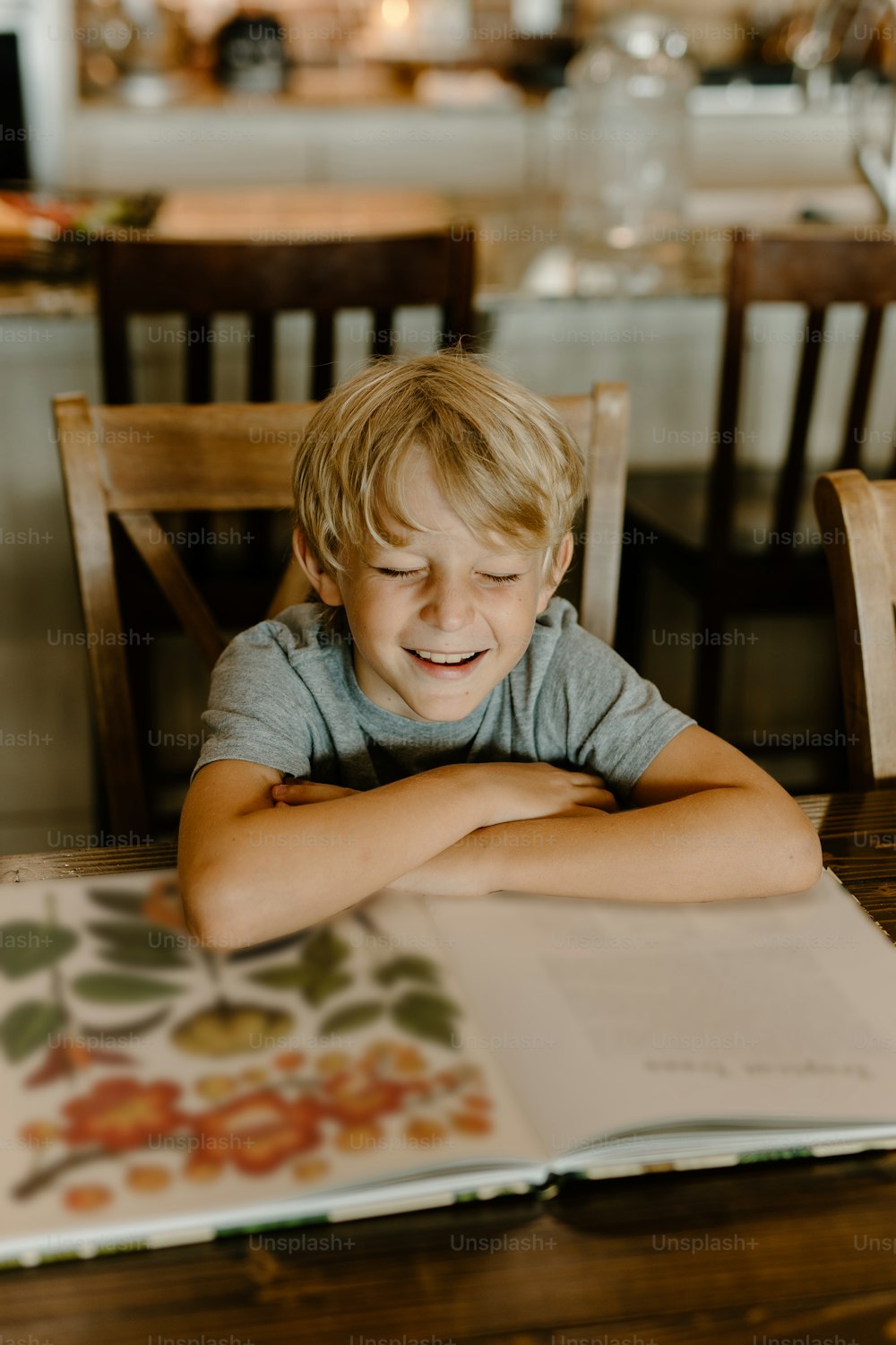 a little boy sitting at a table with a book