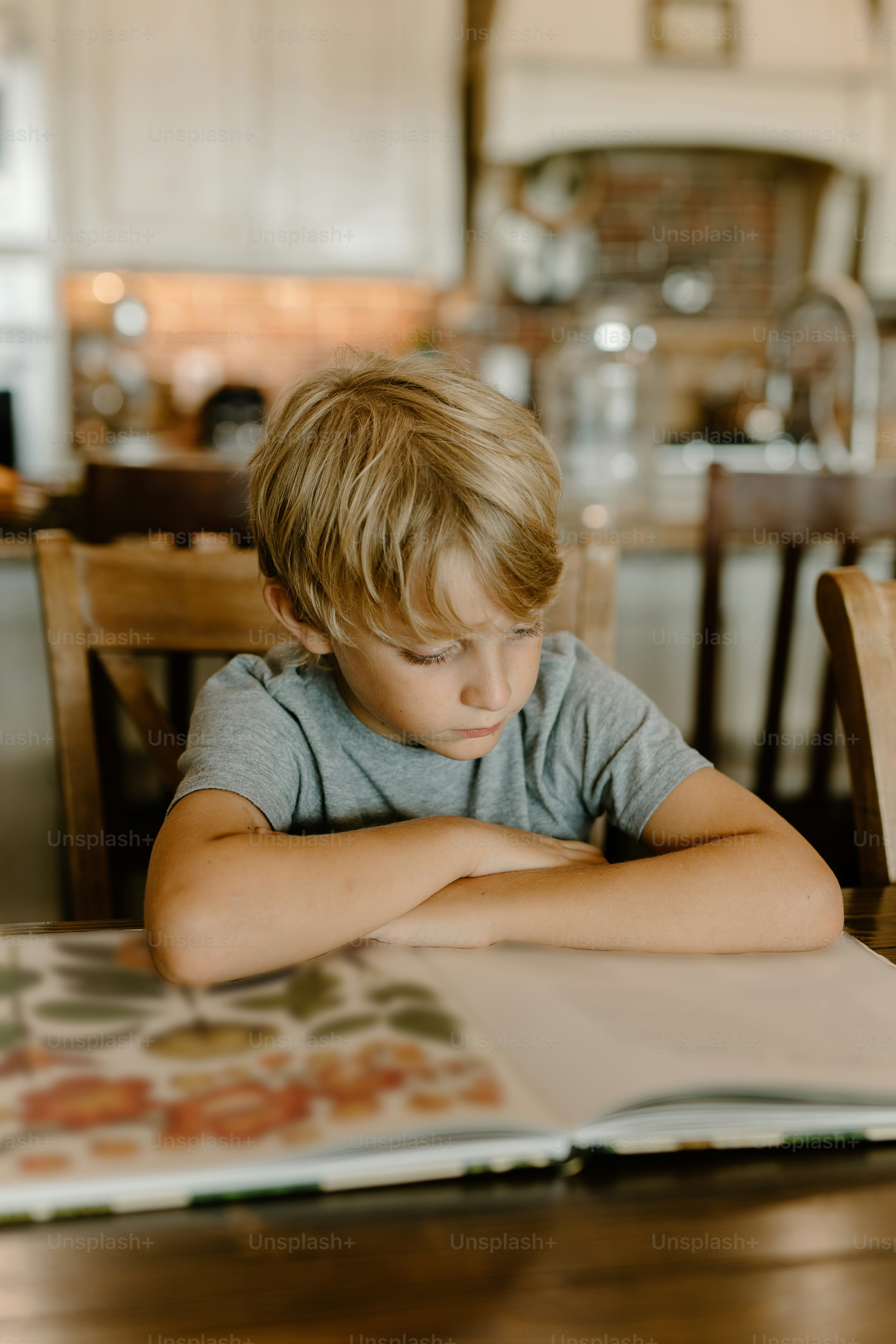 a young boy sitting at a table reading a book