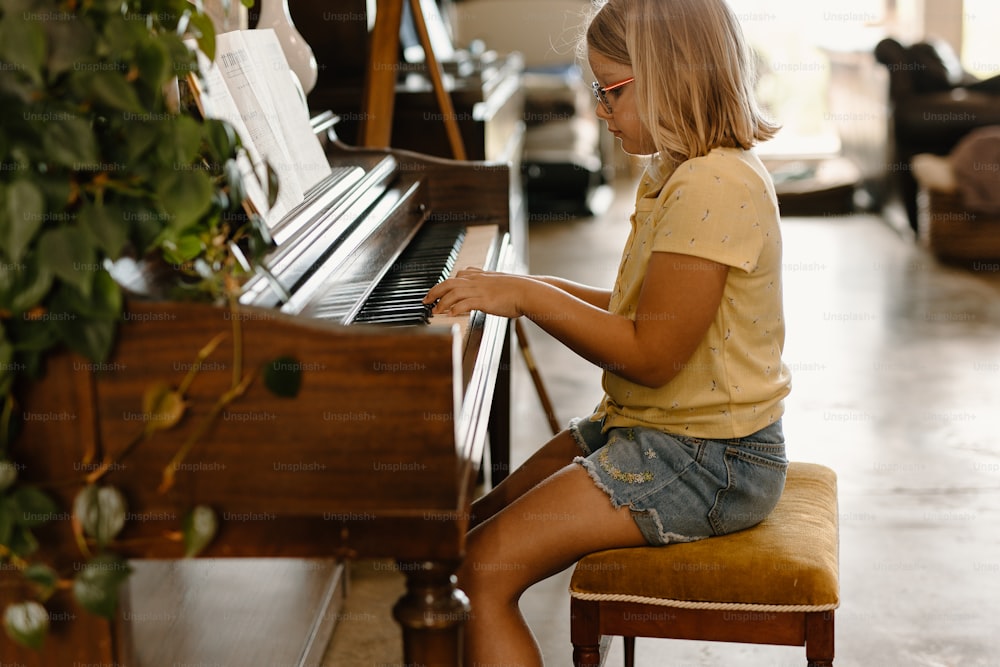 a young girl sitting at a piano playing the piano