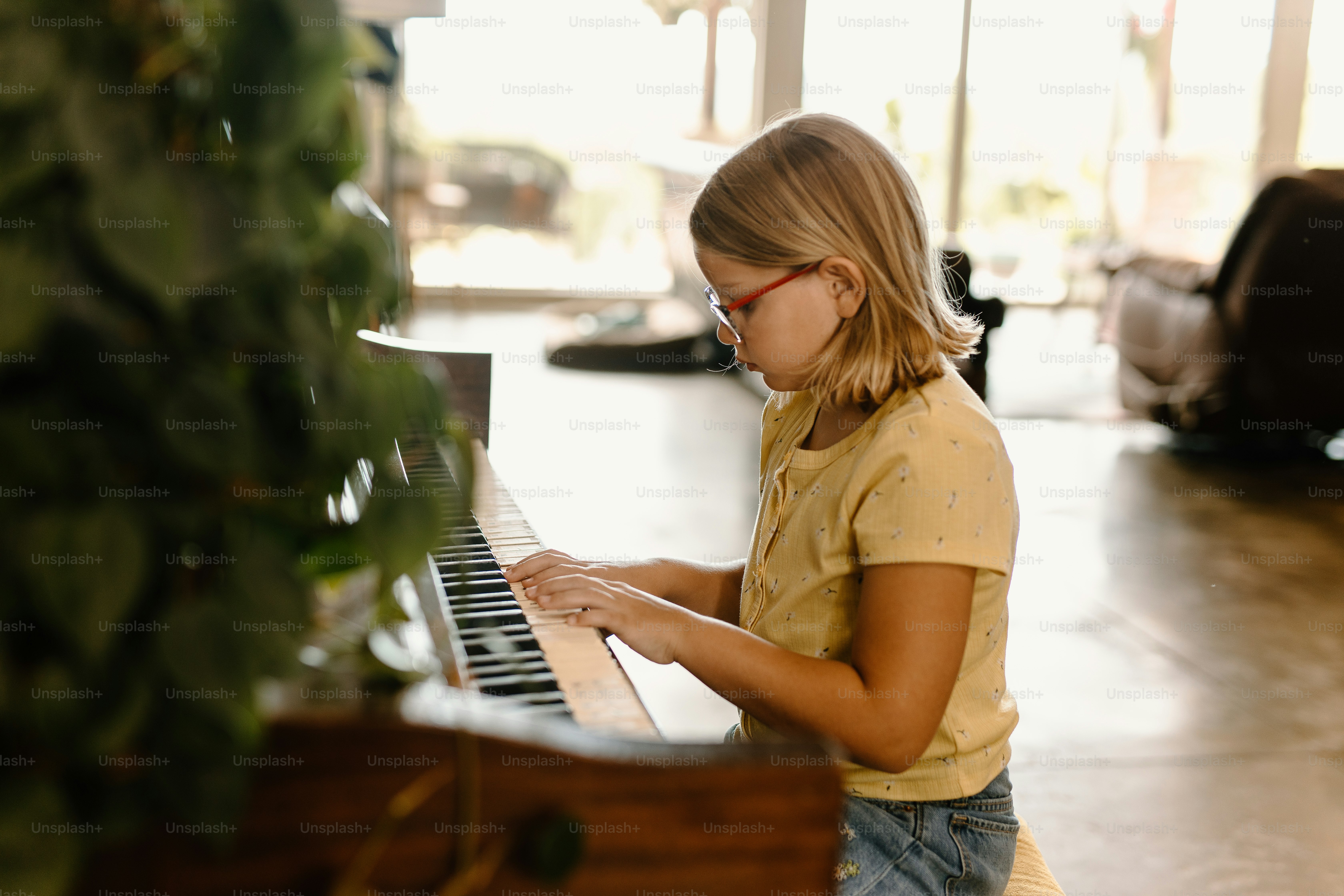a young girl playing a piano in a room