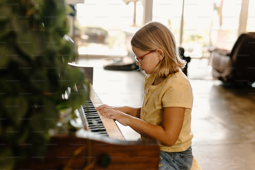 uma menina jovem tocando um piano em um quarto
