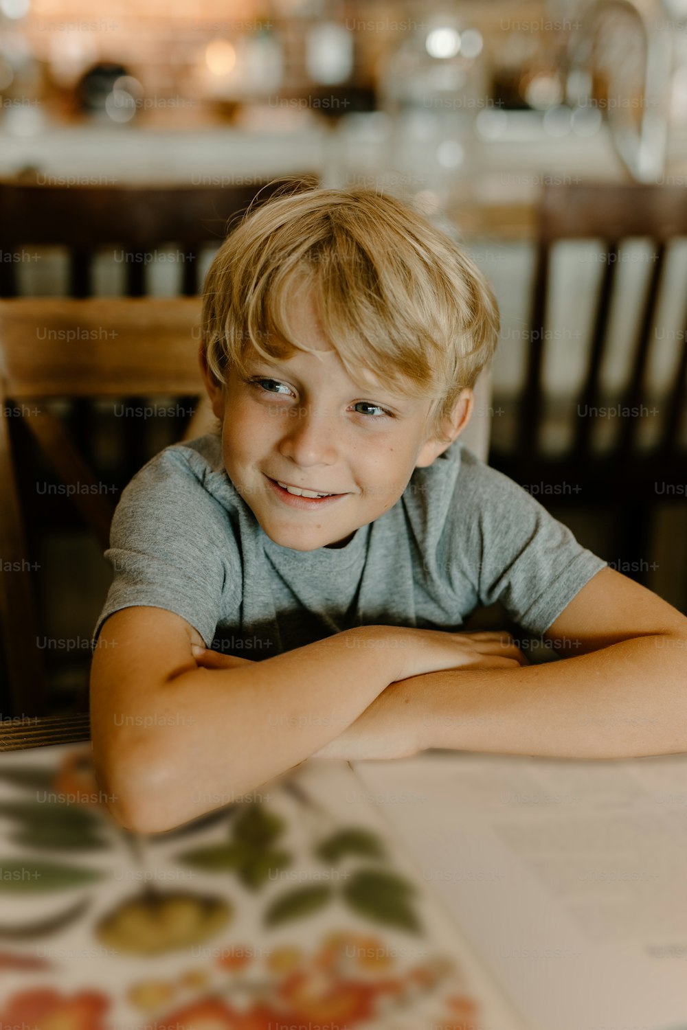Ein kleiner Junge, der mit einem Buch an einem Tisch sitzt
