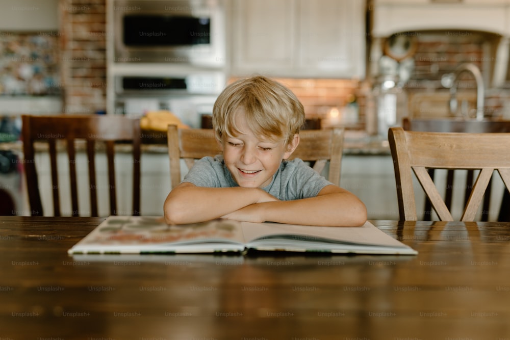 Ein kleiner Junge, der an einem Tisch sitzt und ein Buch liest