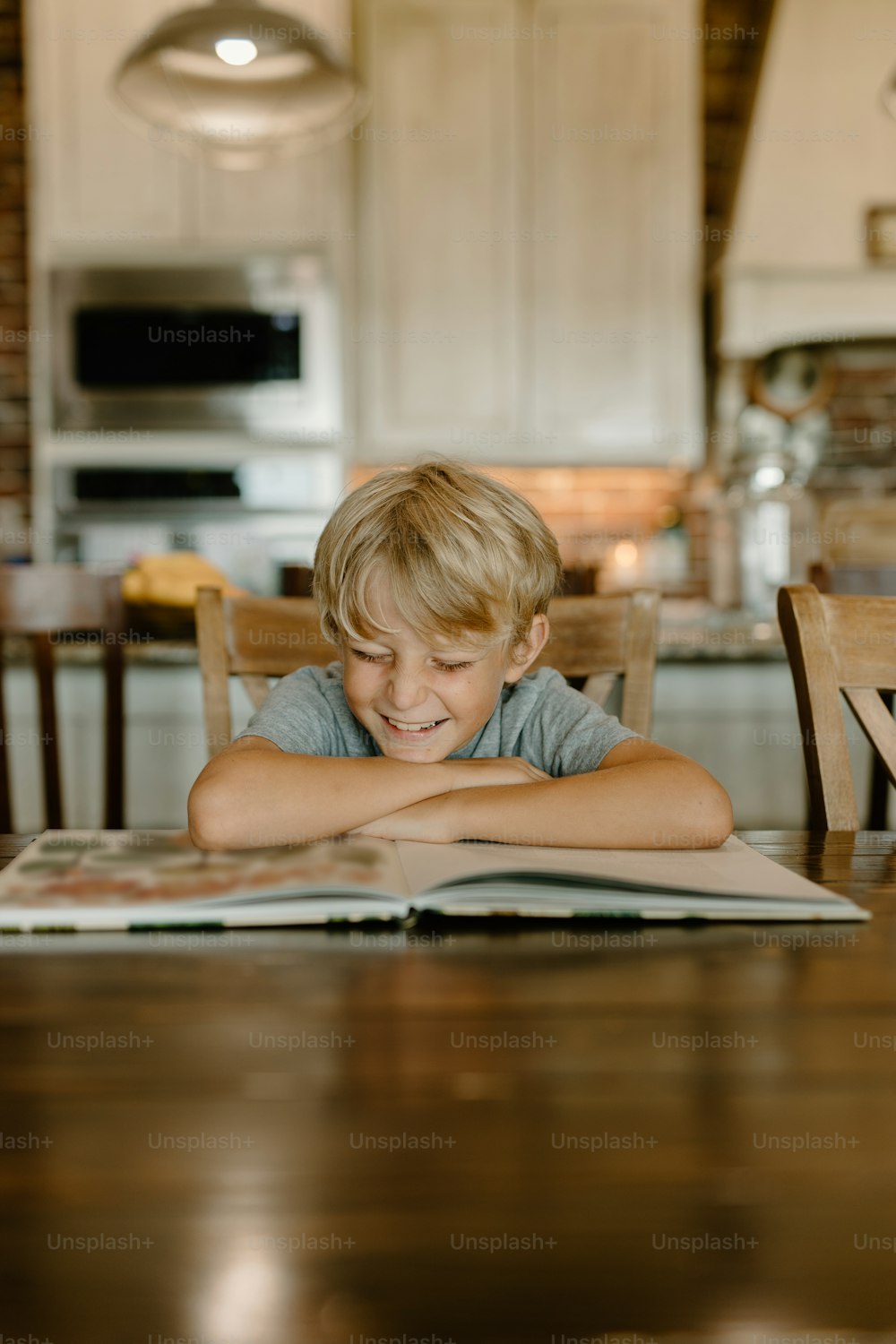 a young boy sitting at a table reading a book