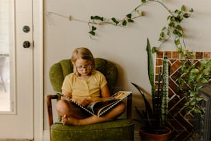 a little girl sitting in a chair reading a book