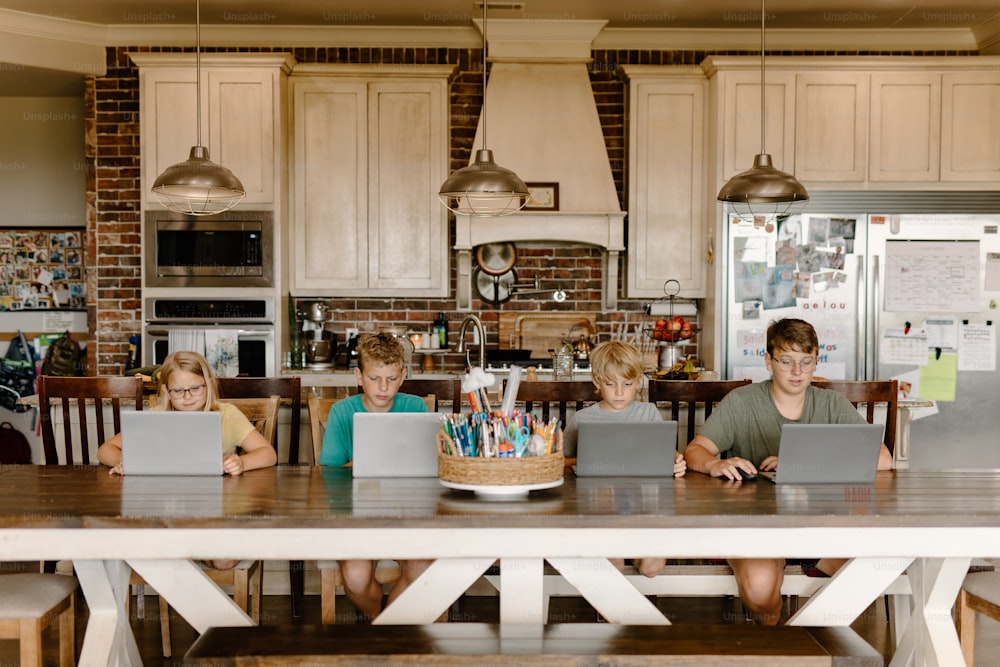 Un gruppo di bambini seduti a un tavolo con computer portatili