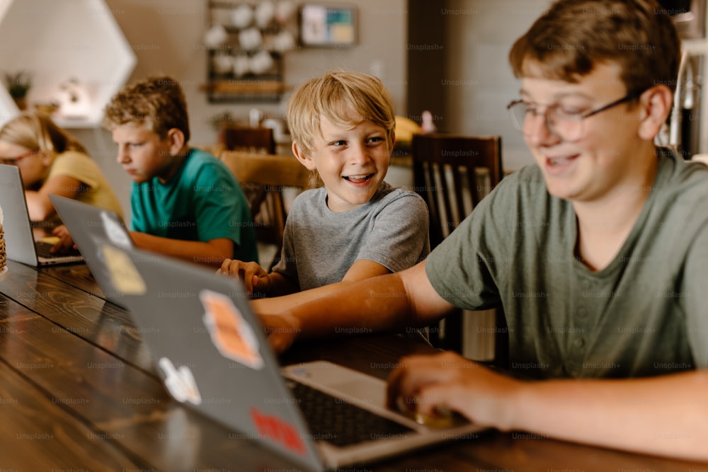 um grupo de meninos sentados em uma mesa com laptops