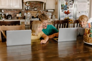 a group of kids sitting at a table with laptops