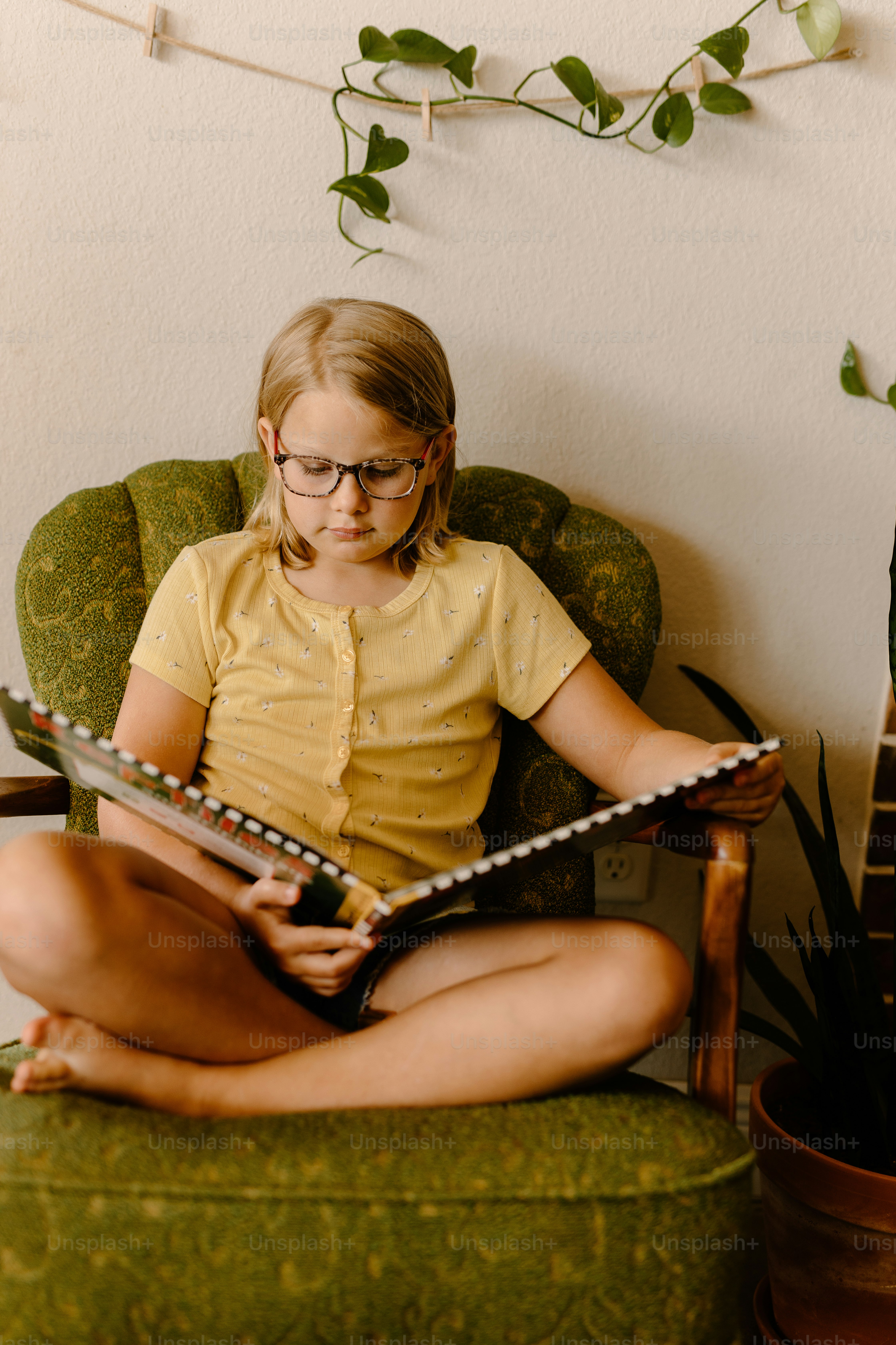 une petite fille assise sur une chaise en train de lire un livre