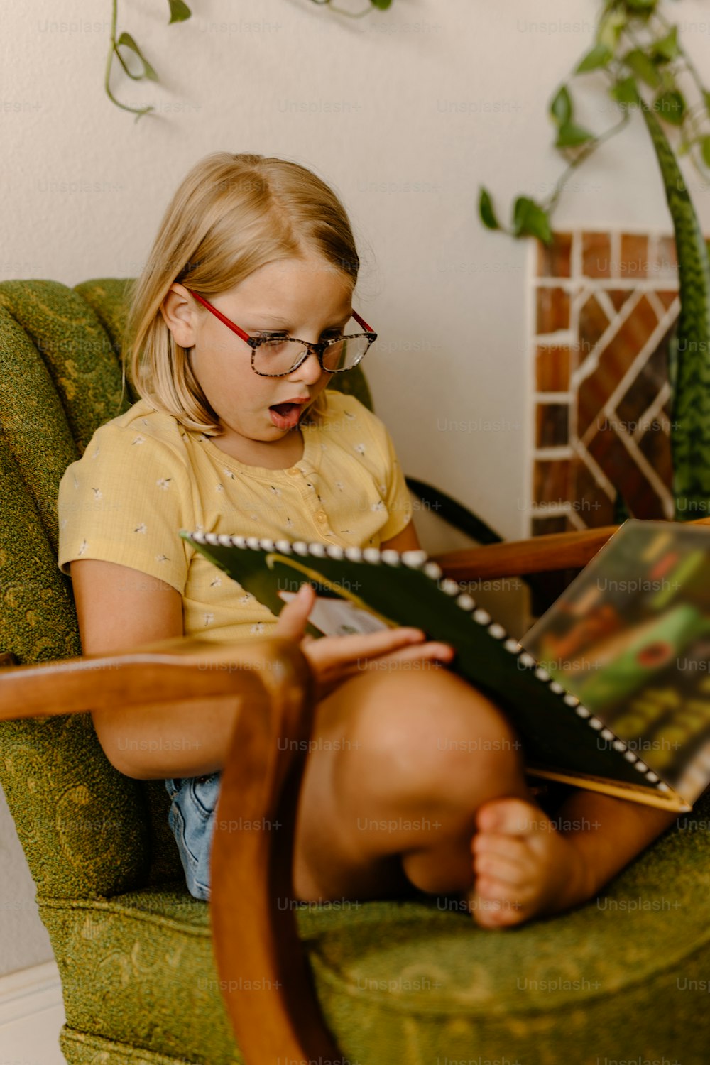 Ein kleines Mädchen, das auf einem Stuhl sitzt und ein Buch liest