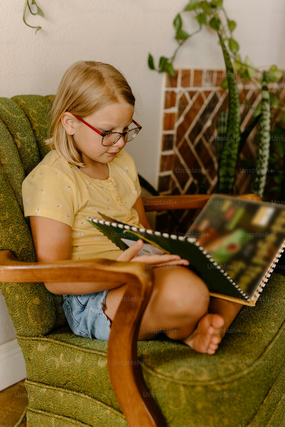 a little girl sitting in a chair reading a book