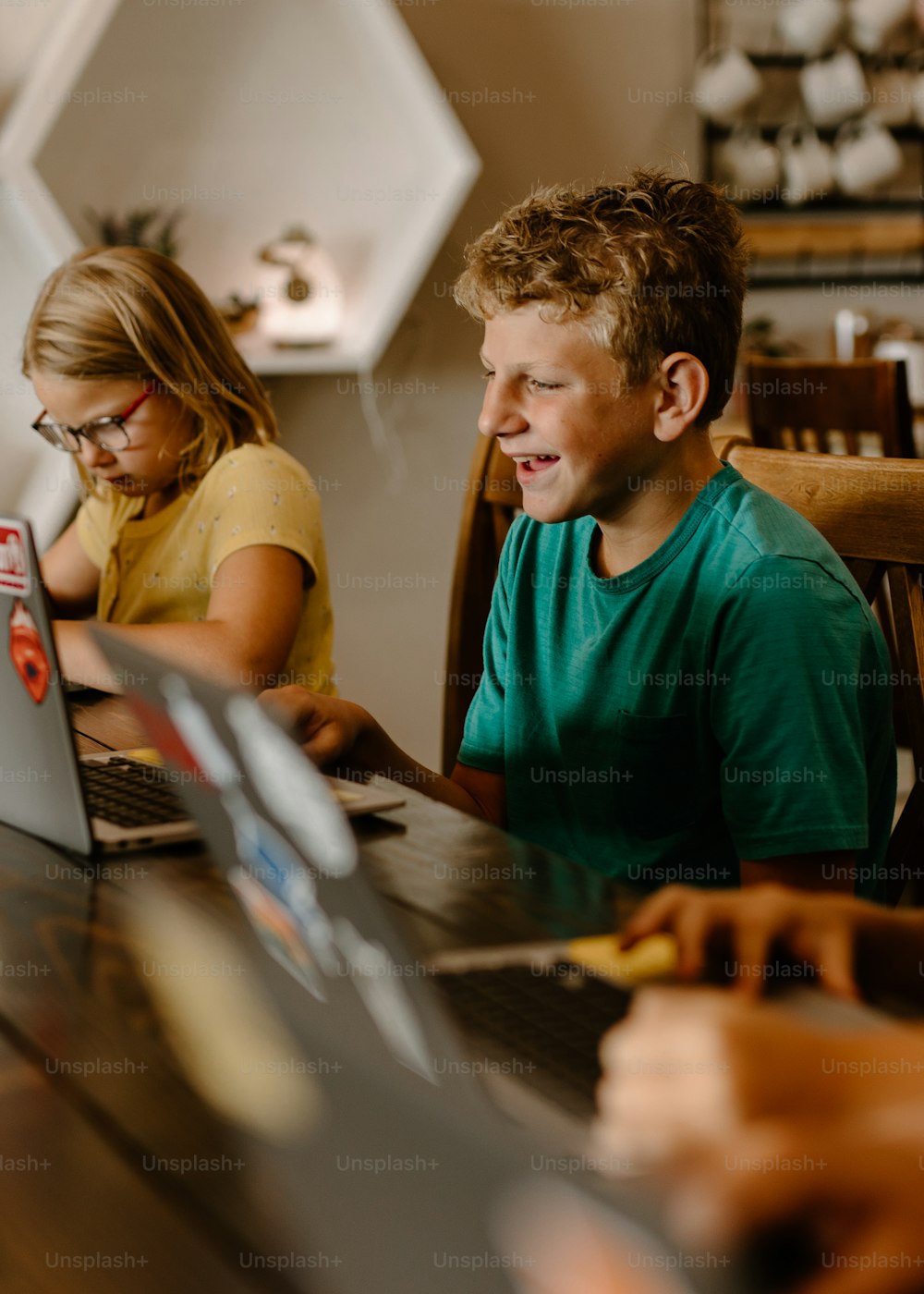 um menino e uma menina sentados em uma mesa com um laptop