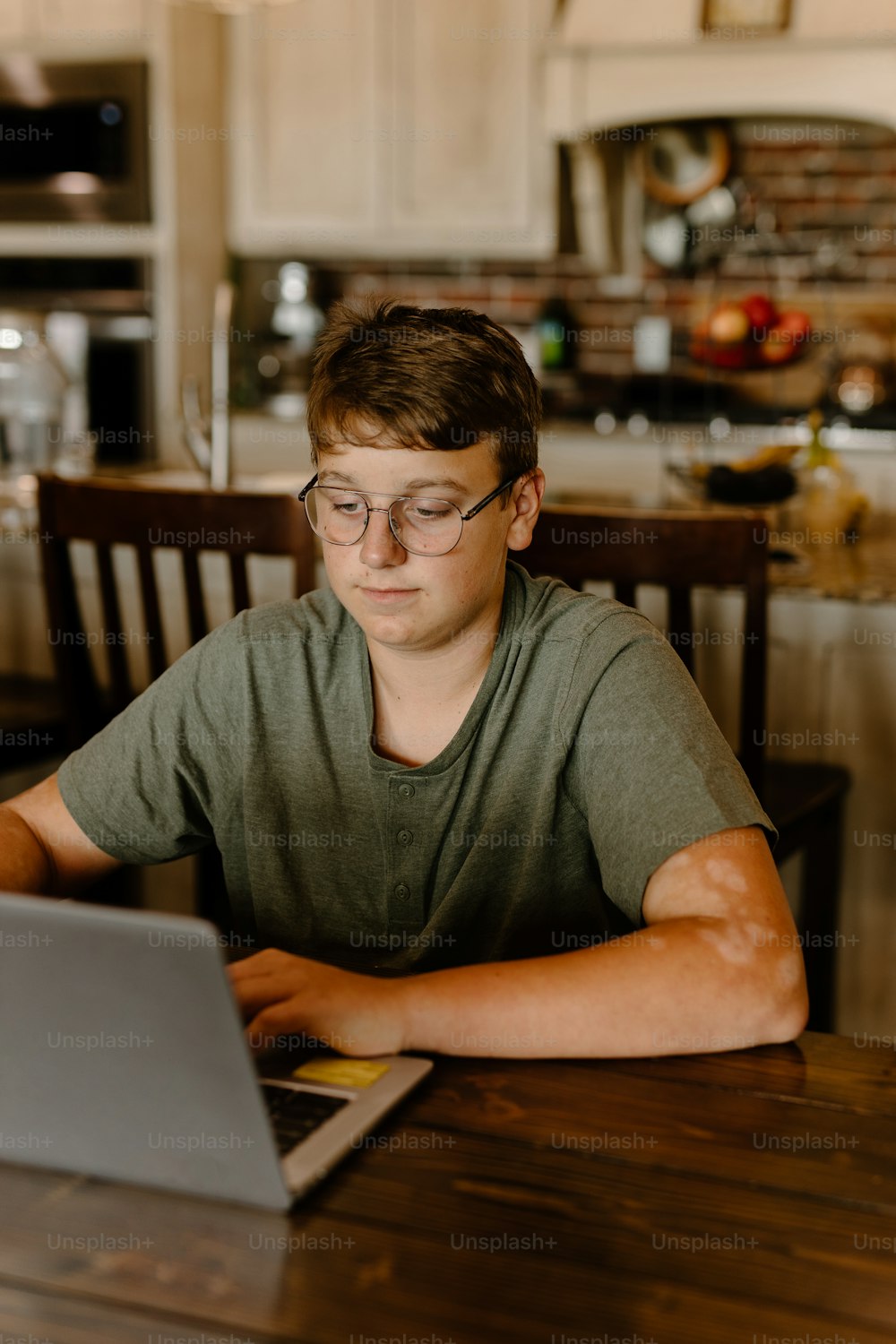 a young man sitting at a table using a laptop computer