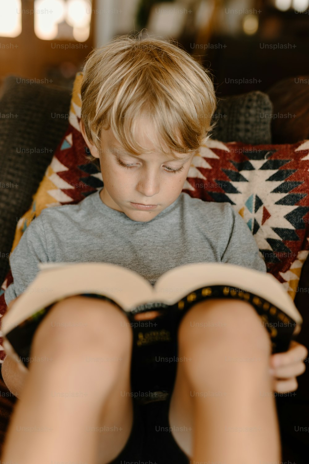 Un jeune garçon assis sur un canapé en train de lire un livre