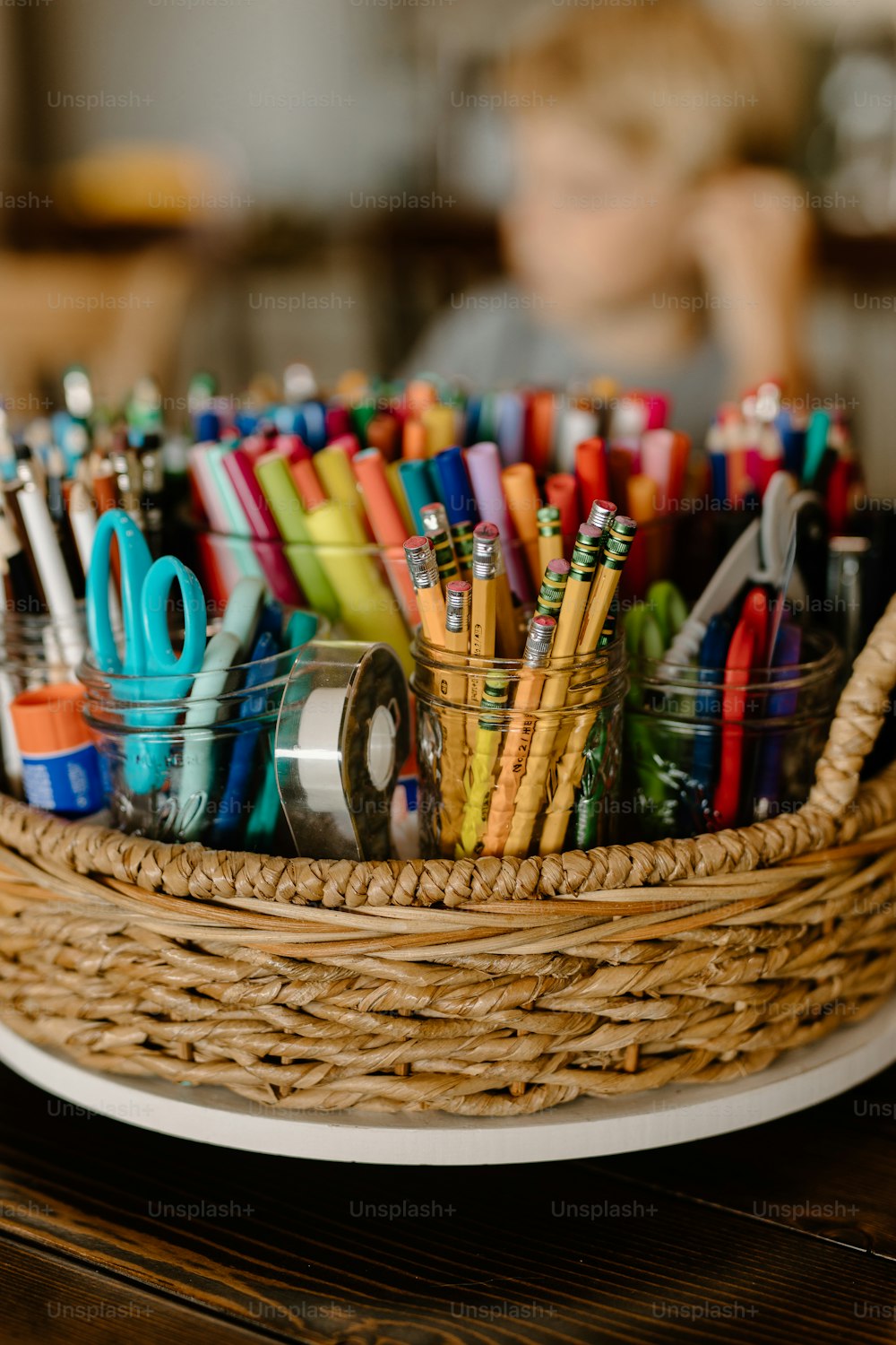 Un panier rempli de nombreux stylos et ciseaux de différentes couleurs