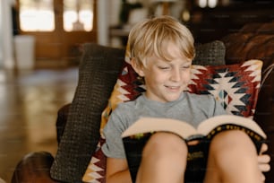 의자에 앉아 책을 읽고 있는 어린 소년