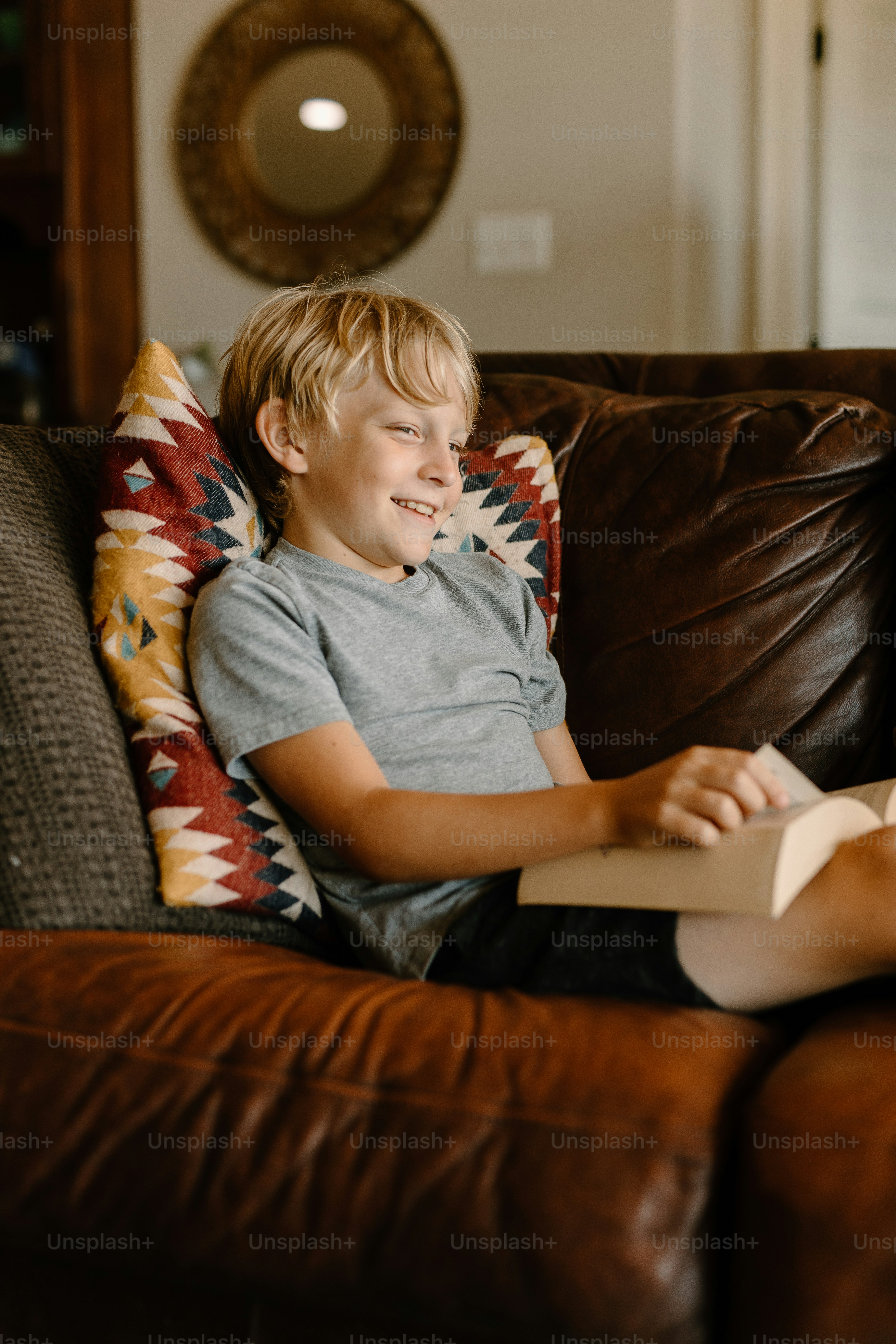 a young boy sitting on a couch reading a book