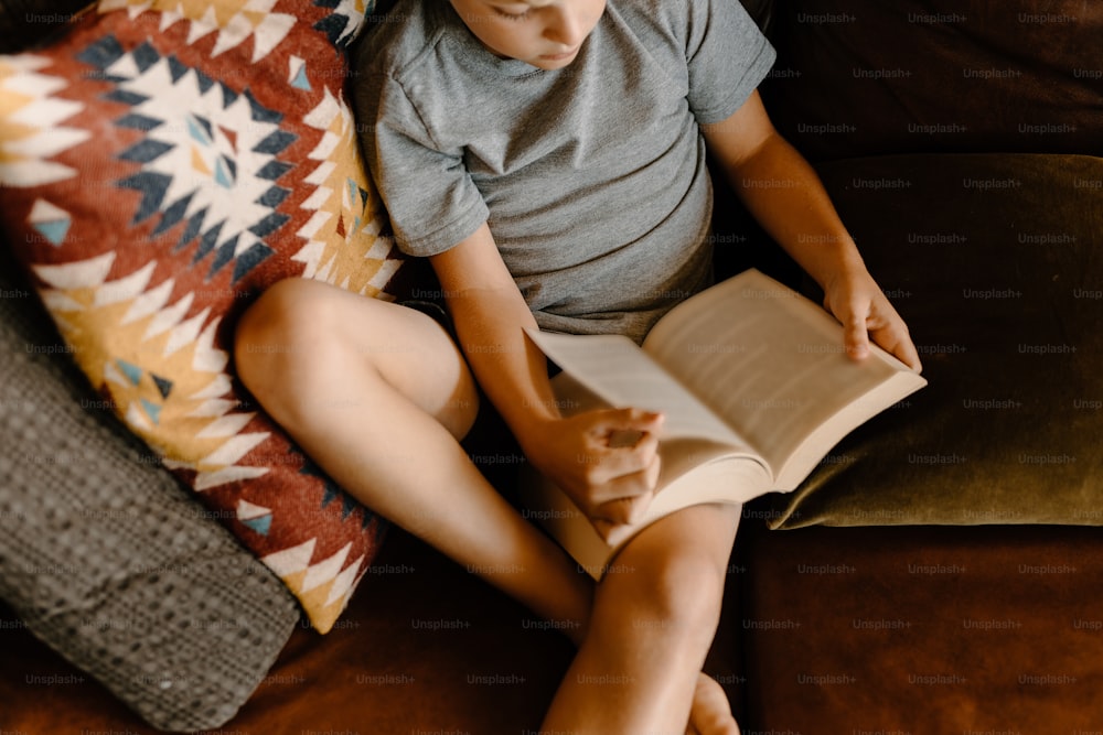 소파에 앉아 책을 읽고 있는 어린 소년