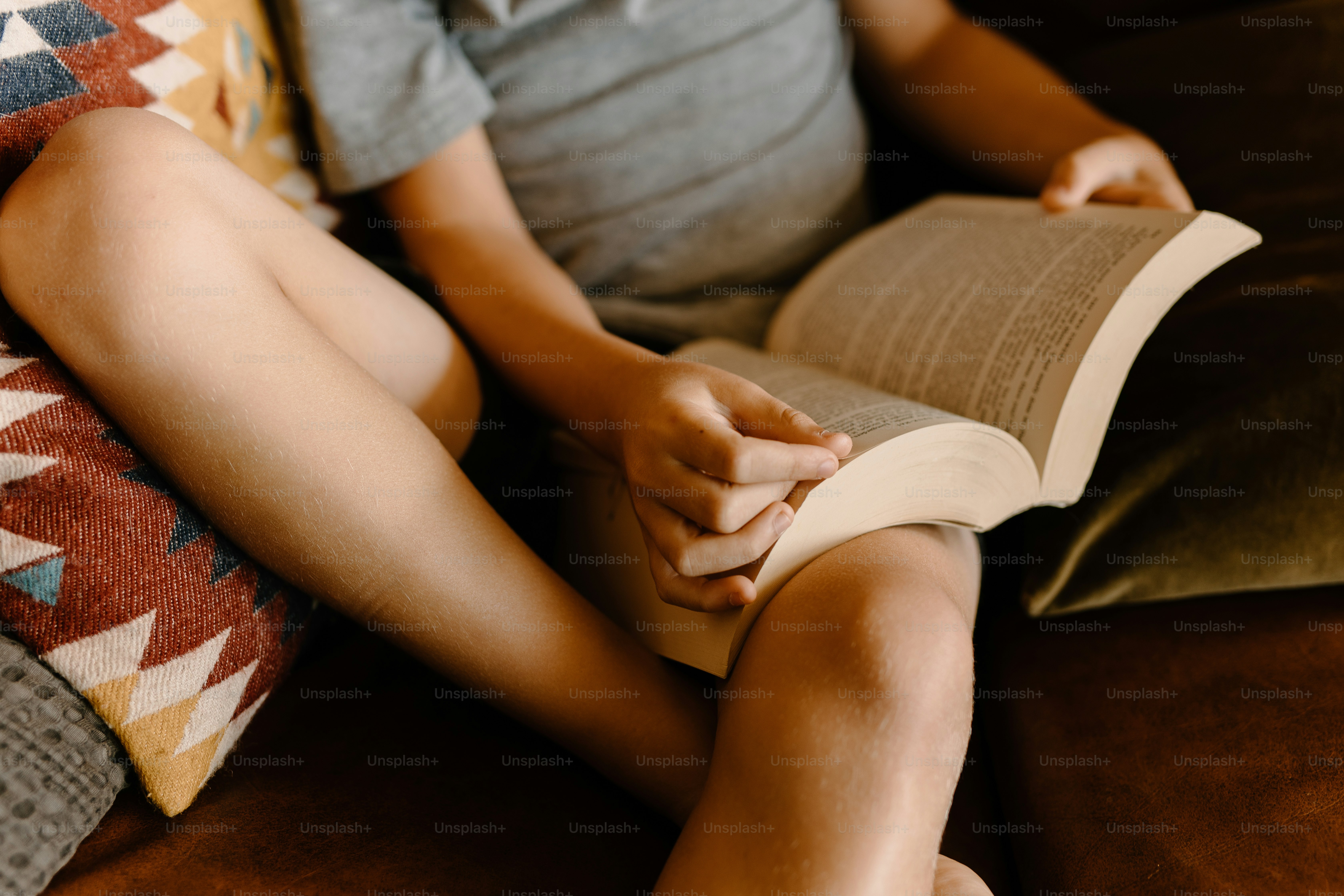 eine Person, die auf einer Couch sitzt und ein Buch liest