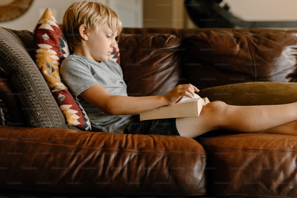 Un niño sentado en un sofá leyendo un libro
