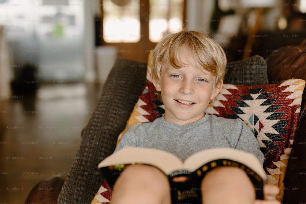 Ein kleiner Junge, der auf einem Stuhl sitzt und ein Buch hält
